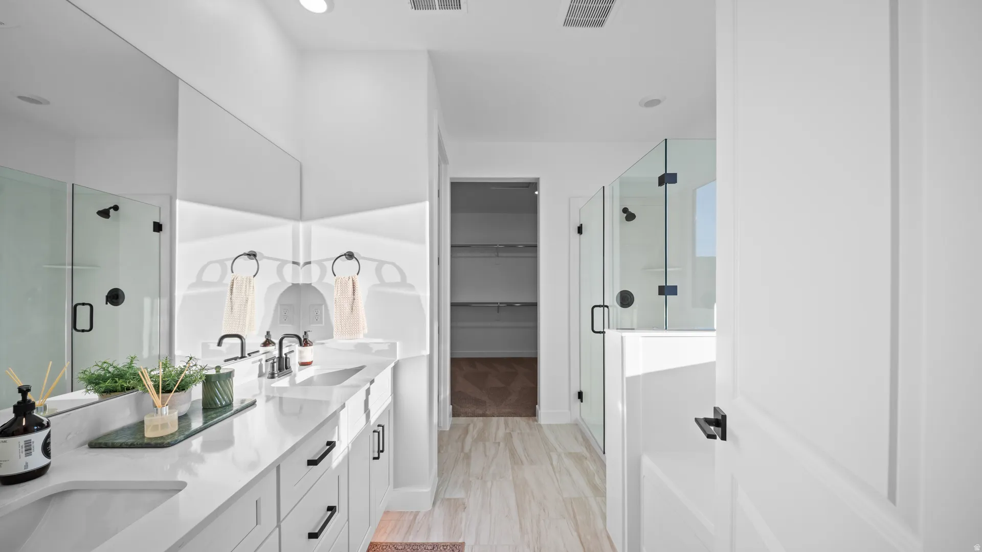 Full bathroom featuring double vanity, a shower stall, a spacious closet, and light wood-style floors