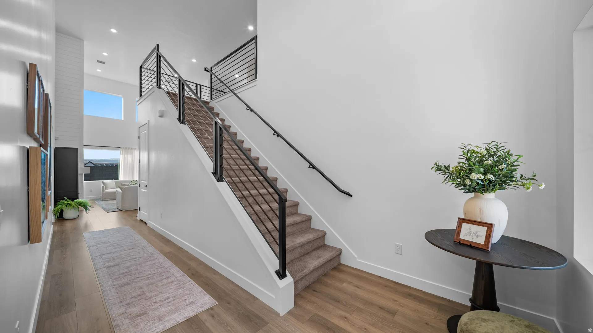 Stairway featuring a high ceiling, wood finished floors, and recessed lighting