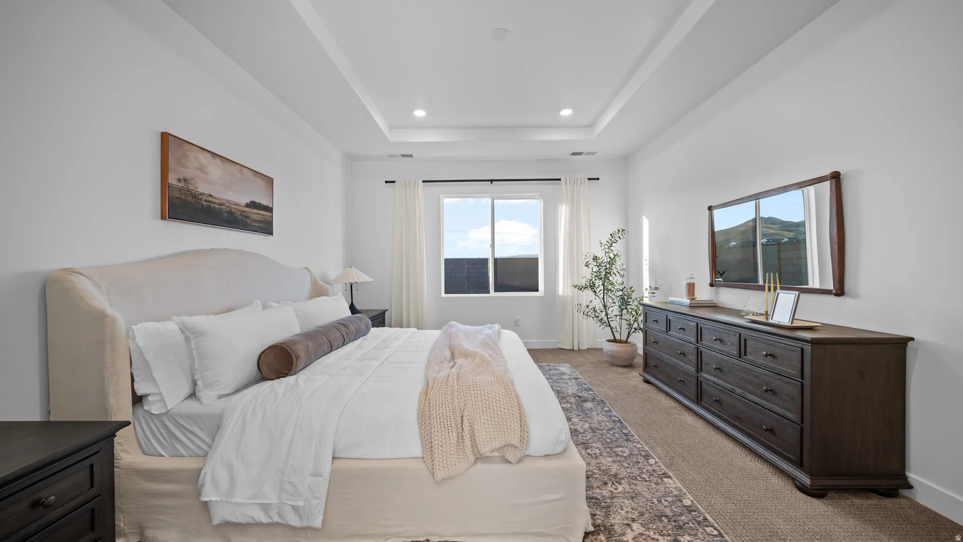 Bedroom with light colored carpet and a raised ceiling