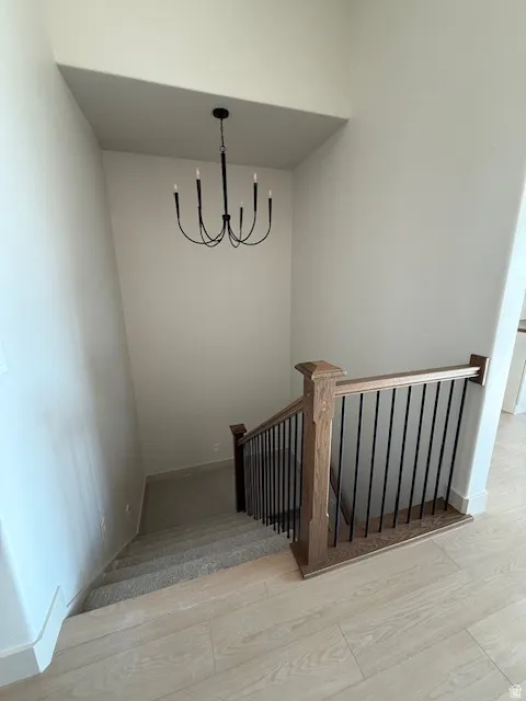 Staircase with wood finished floors and a chandelier