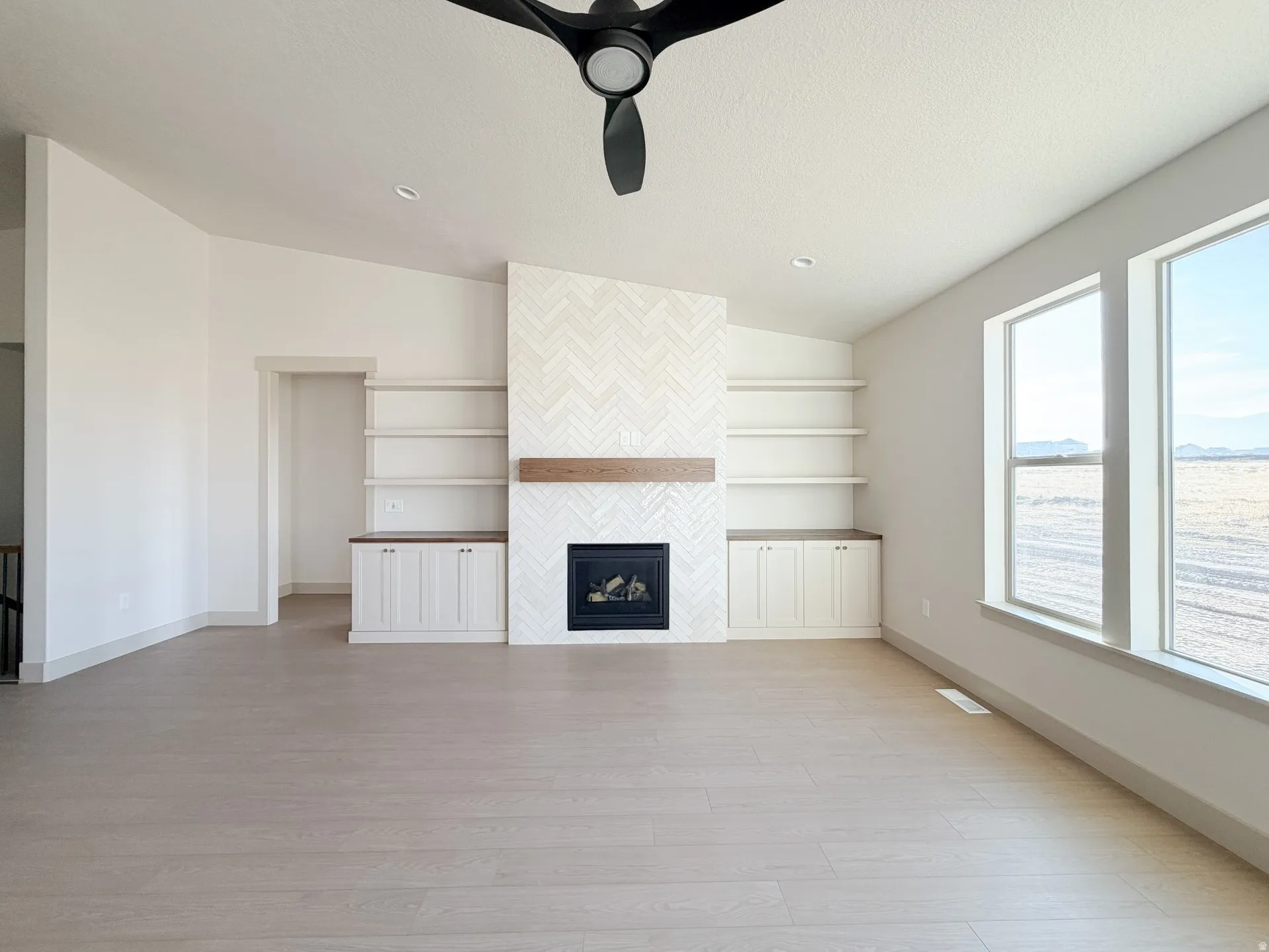 Unfurnished living room with light wood finished floors, a fireplace, and ceiling fan