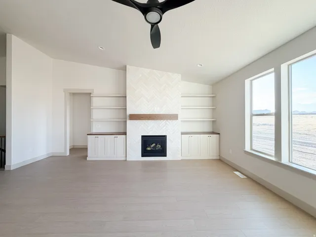 Unfurnished living room with light wood finished floors, a fireplace, and ceiling fan