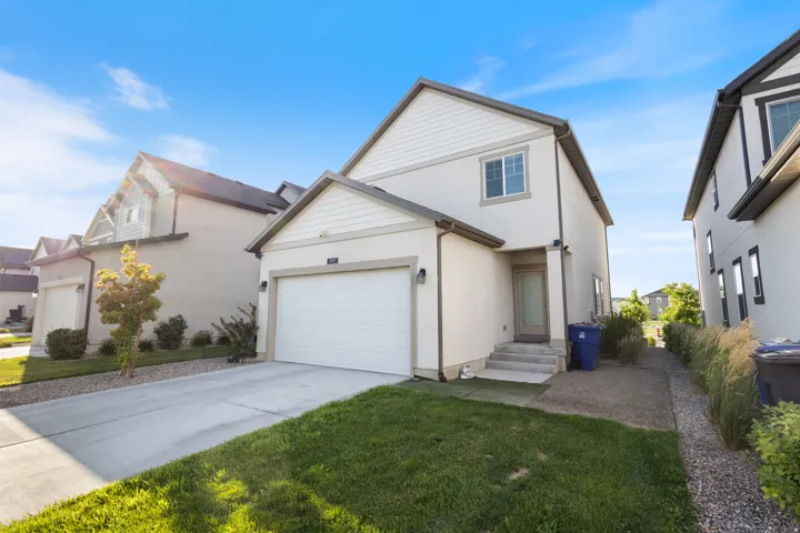 Traditional-style home with driveway, stucco siding, an attached garage, and a front lawn