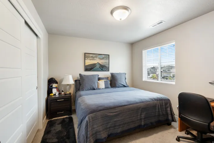 Carpeted bedroom featuring a closet, a textured ceiling, and a desk