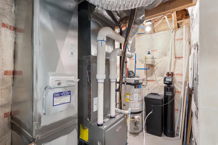 Utility room featuring secured water heater and heating unit