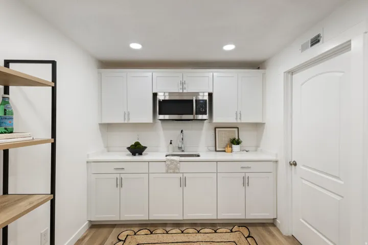 Kitchen with white cabinetry, backsplash, light wood finished floors, and recessed lighting
