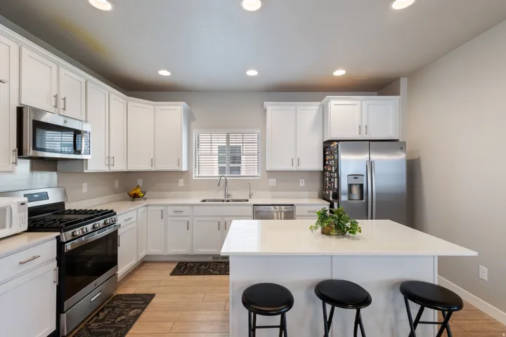 Kitchen featuring a breakfast bar area, appliances with stainless steel finishes, light wood-style flooring, white cabinets, and a kitchen island