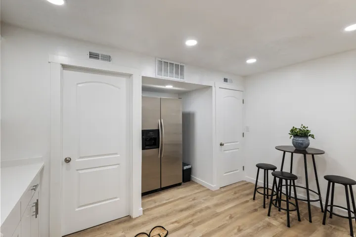 Kitchen with stainless steel fridge, light wood-type flooring, recessed lighting, and white cabinetry