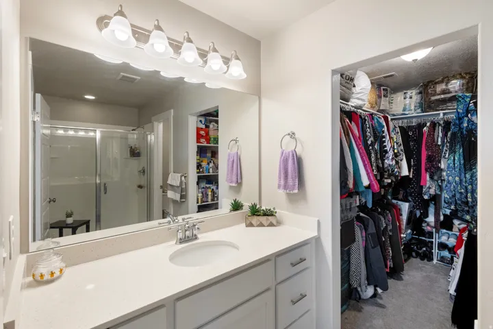 Full bath with a spacious closet, a stall shower, and vanity