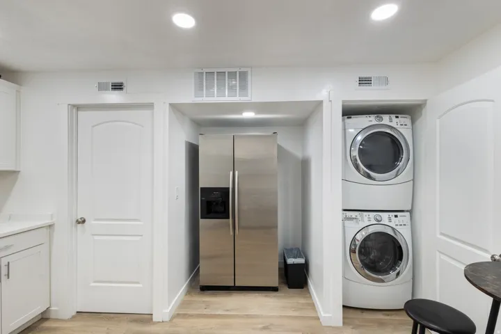 Laundry area with estacked washer and dryer, light wood finished floors, and recessed lighting