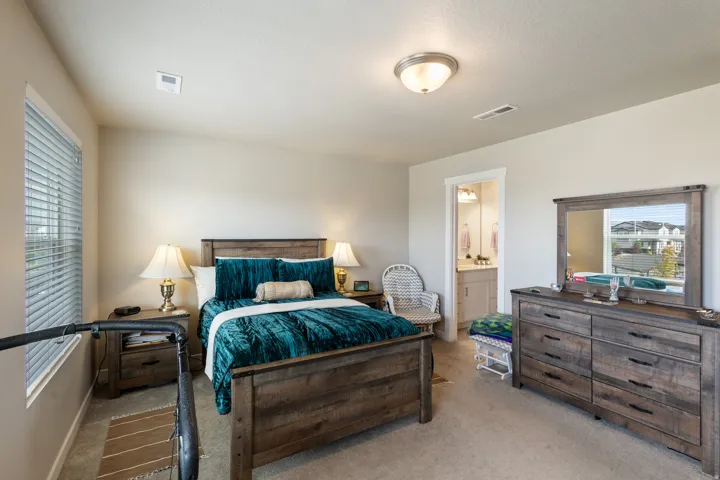 Bedroom featuring multiple windows, carpet floors, and ensuite bath