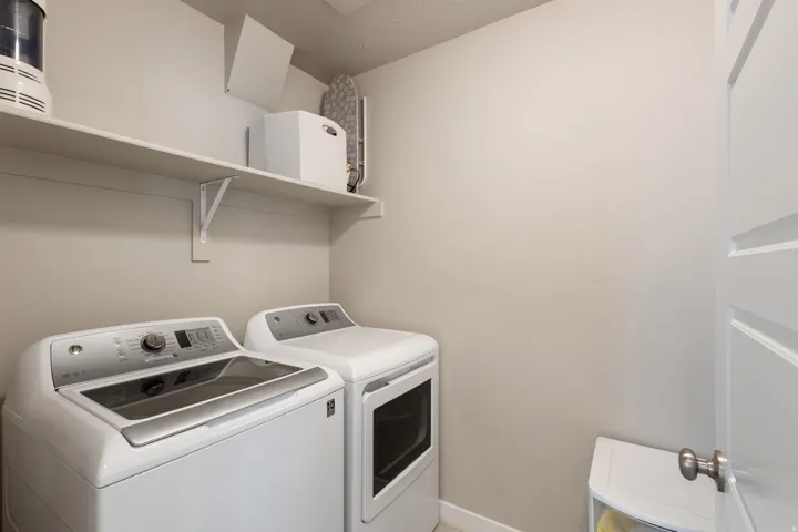Washroom featuring washing machine and dryer and baseboards