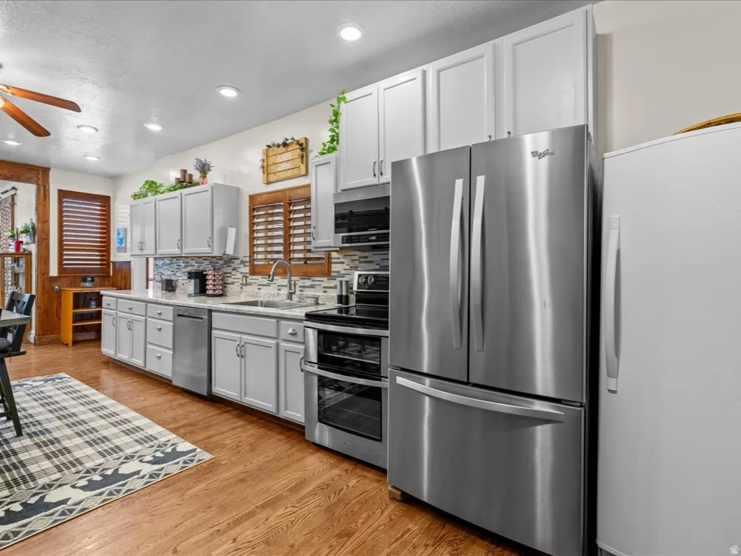 Kitchen featuring appliances with stainless steel finishes, tasteful backsplash, light wood-type flooring, recessed lighting, and ceiling fan