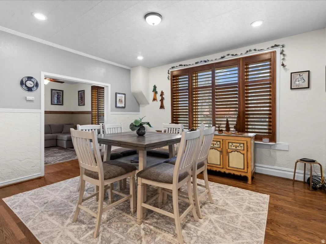 Dining room with a textured wall, dark wood-style floors, recessed lighting, and ornamental molding