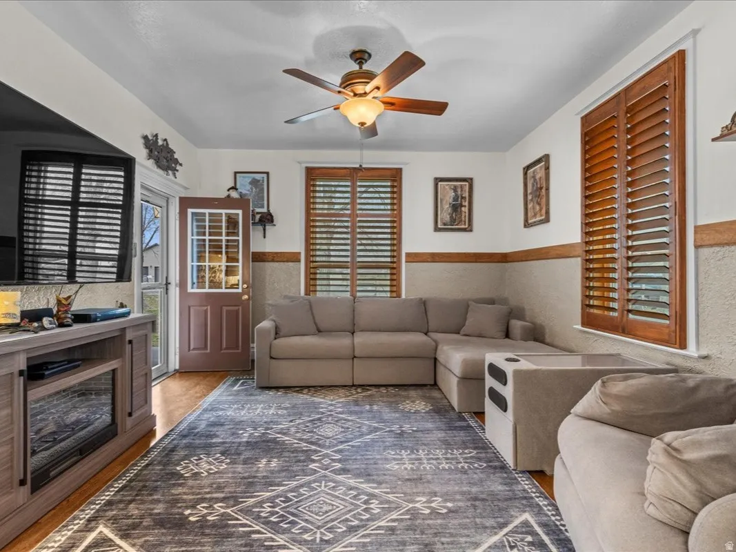 Living area with a ceiling fan and a wainscoted wall