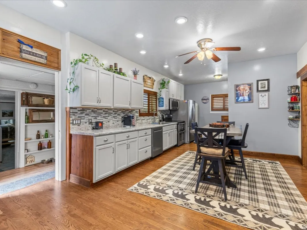Kitchen with a barn door, stainless steel appliances, decorative backsplash, white cabinetry, and light wood-type flooring