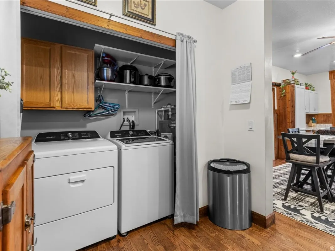 Laundry area featuring dark wood-style flooring, cabinet space, ceiling fan, washer and clothes dryer, and a textured ceiling