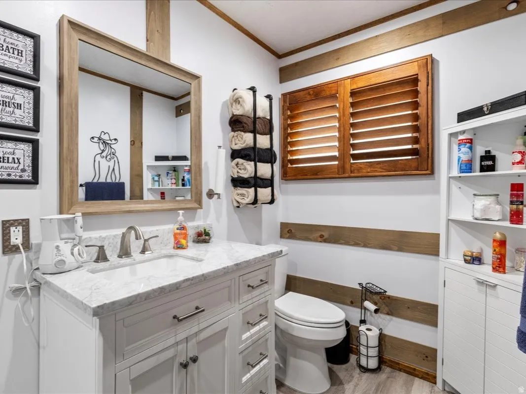Half bathroom featuring vanity, crown molding, and light wood-style flooring