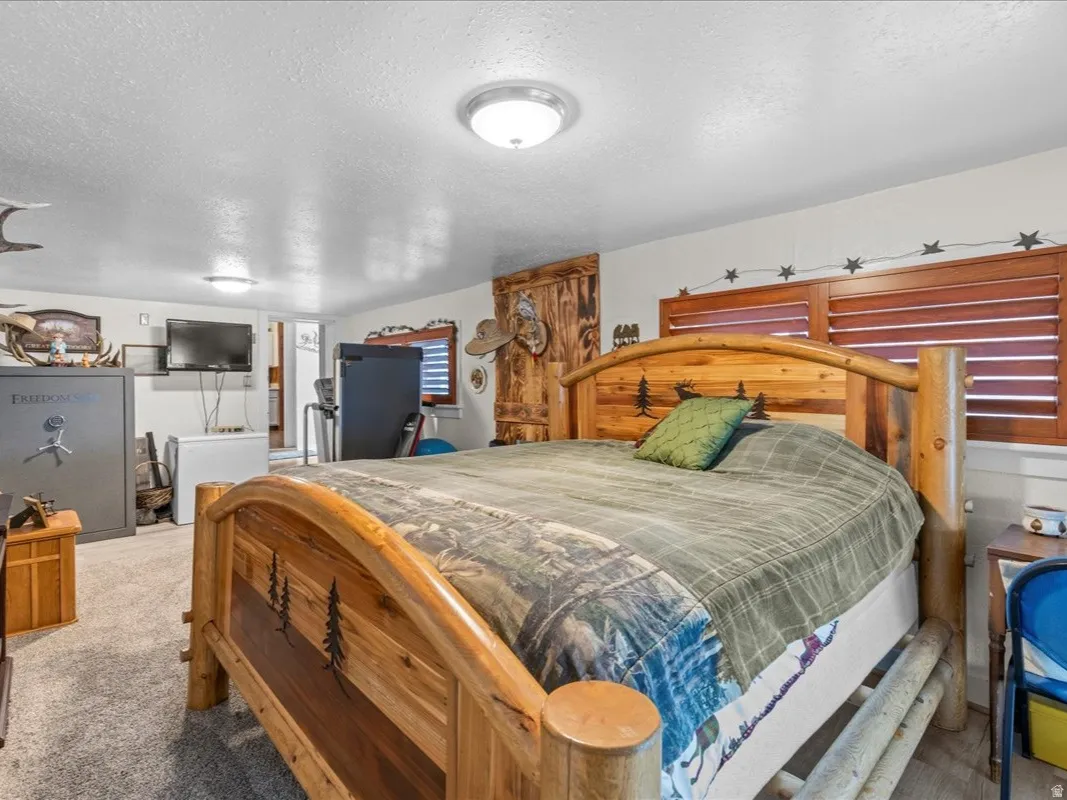 Bedroom with a textured ceiling, carpet flooring, and white refrigerator