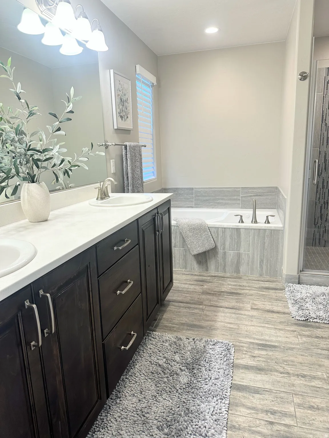 Full bathroom with double vanity, a bath, dark wood finished floors, and a shower stall