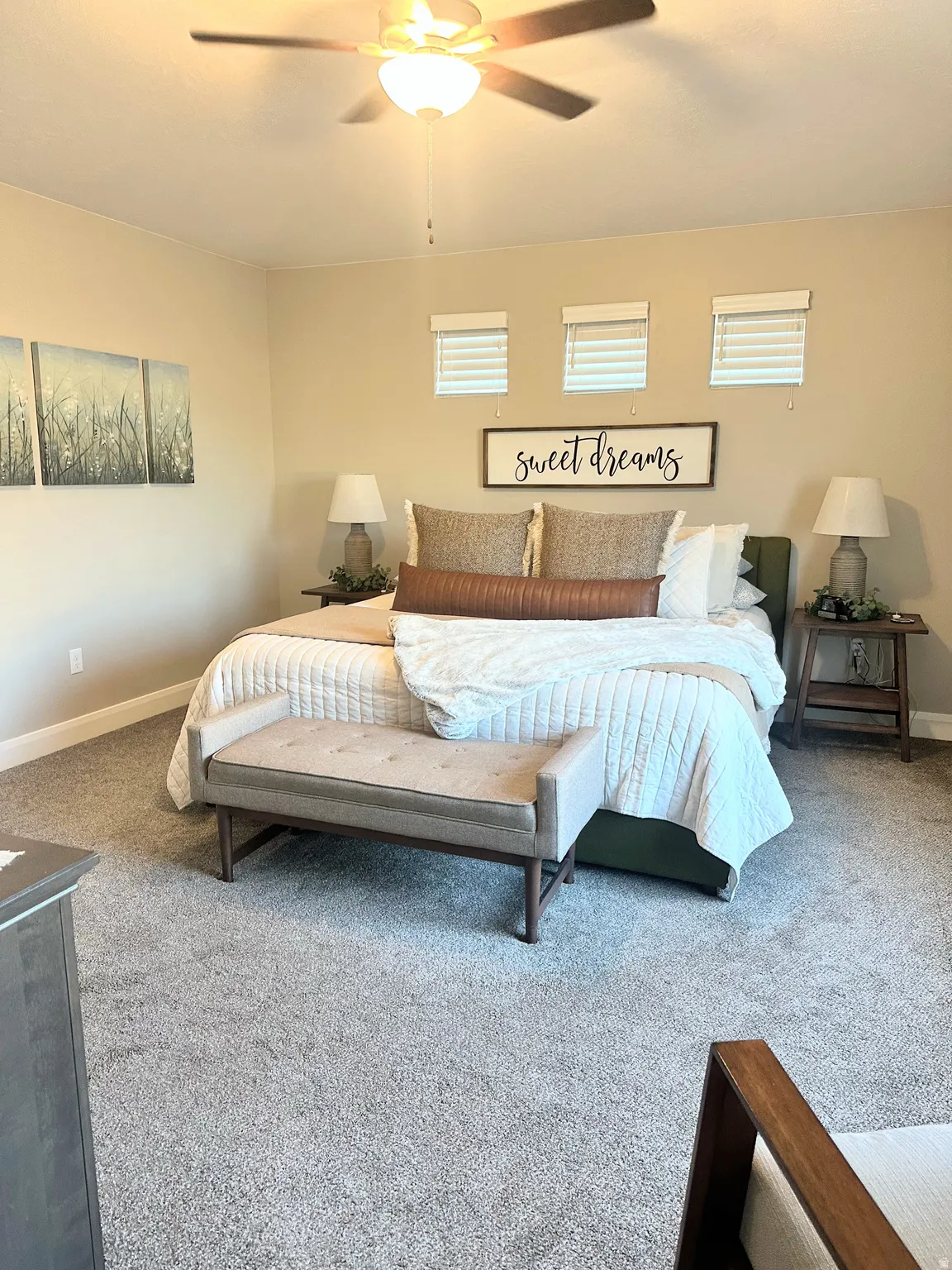 Carpeted bedroom with a ceiling fan and multiple windows