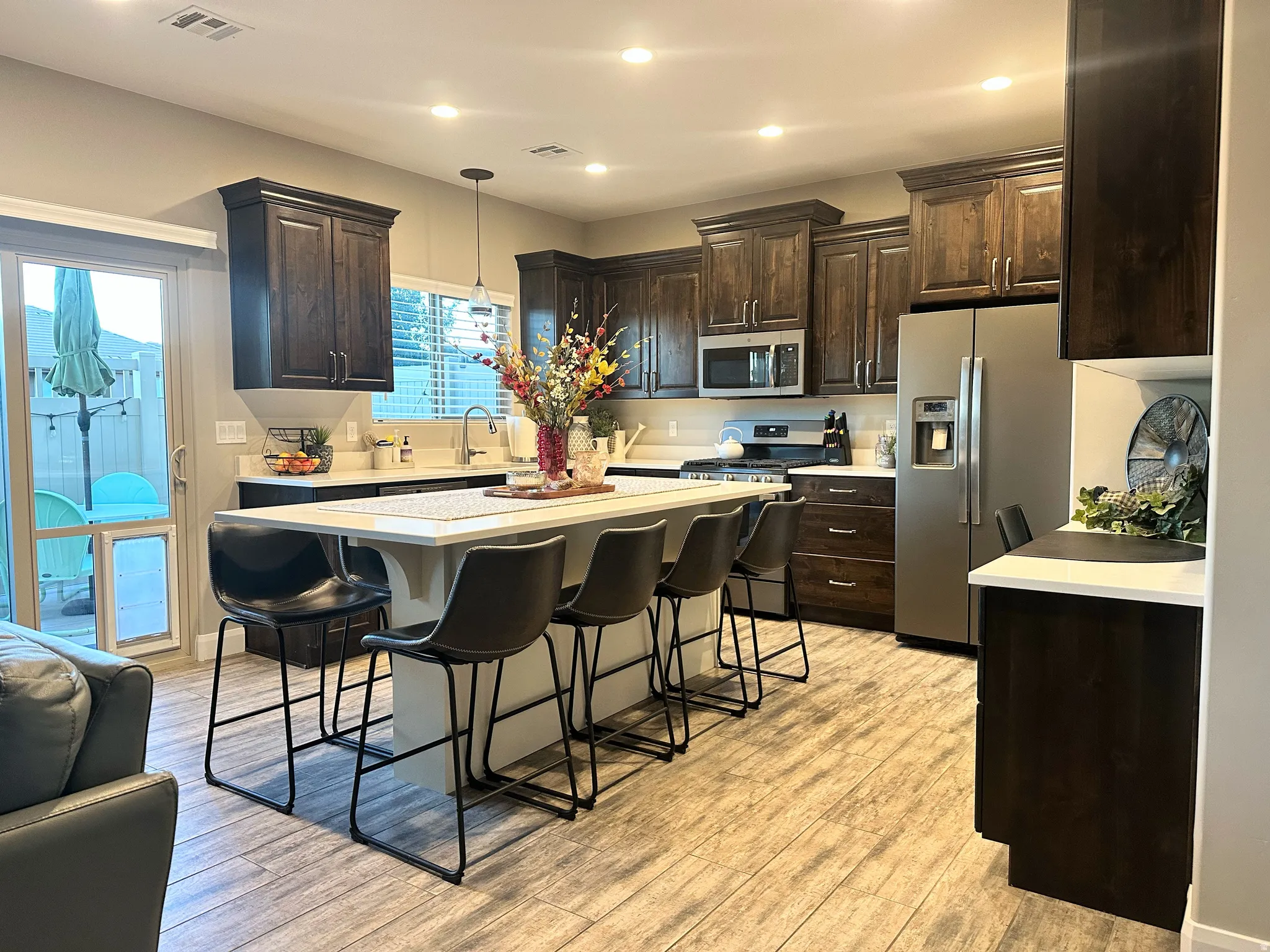Kitchen with stainless steel appliances, a kitchen bar, a center island, dark brown cabinets, and recessed lighting