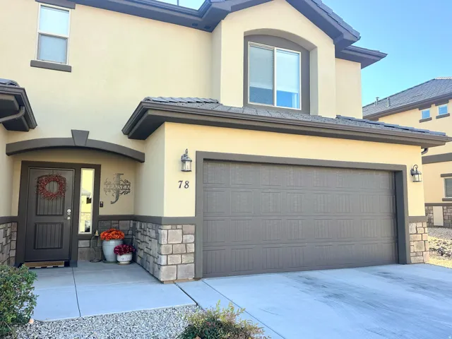 View of front of home with stone siding, stucco siding, and driveway