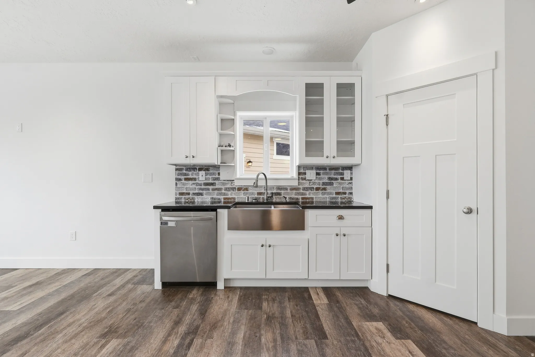 Kitchen with white cabinets, open shelves, dishwasher, and glass insert cabinets