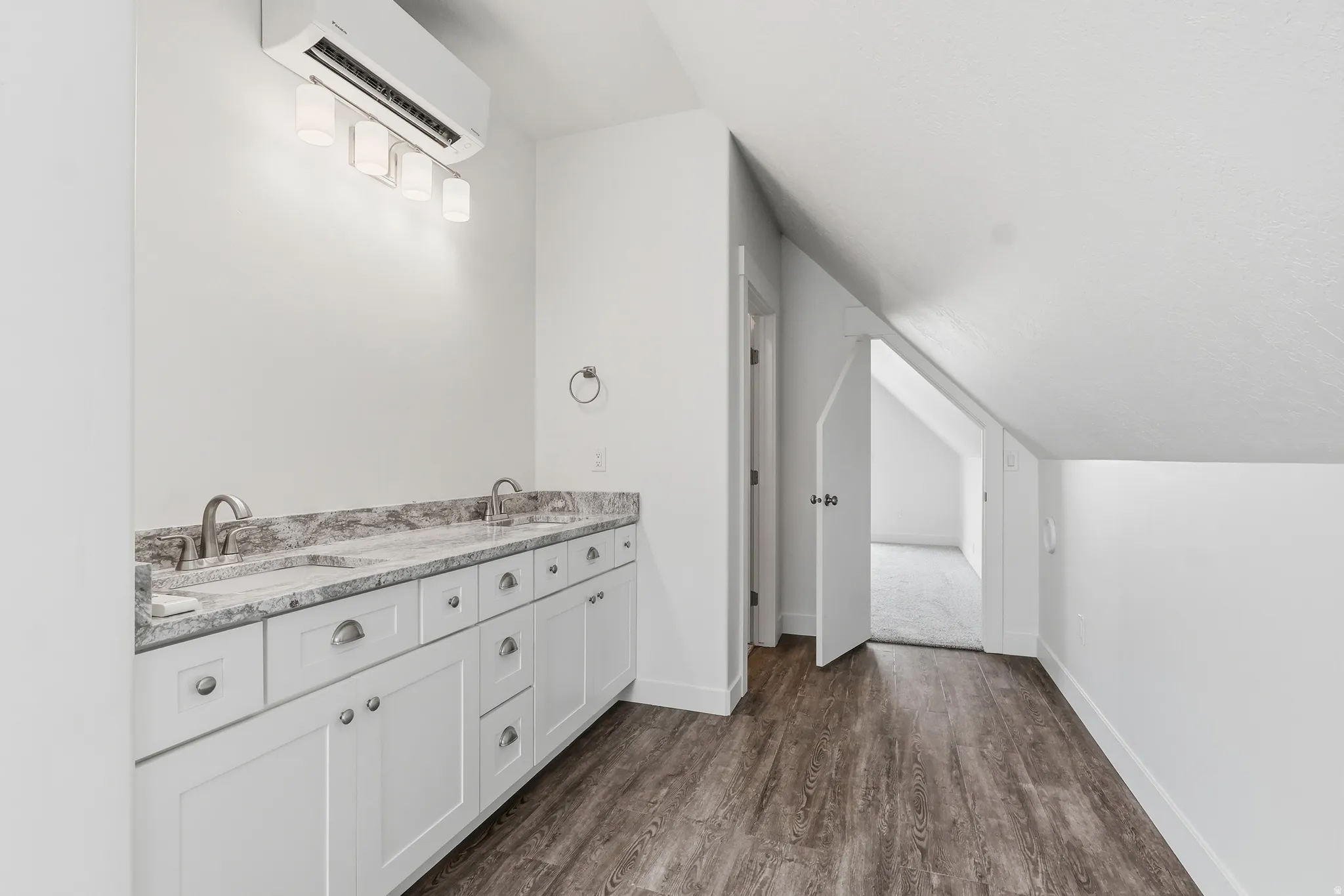 Full bath with double vanity looking toward bedroom with walk-in closet on the left by door.