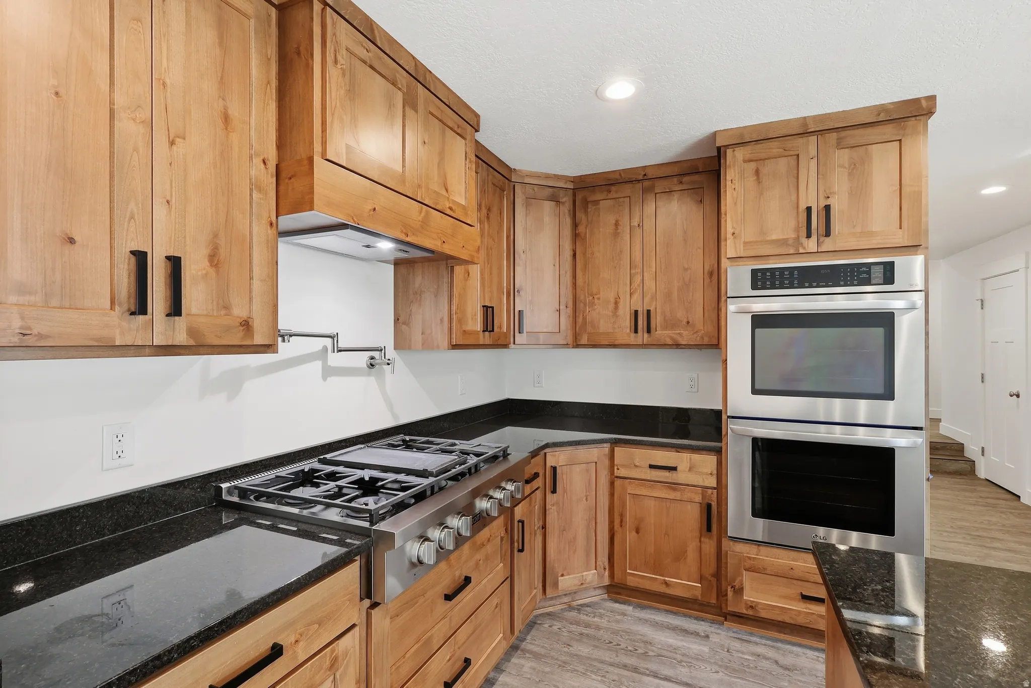 Kitchen with refrigerator, double oven and gas range with pot filler