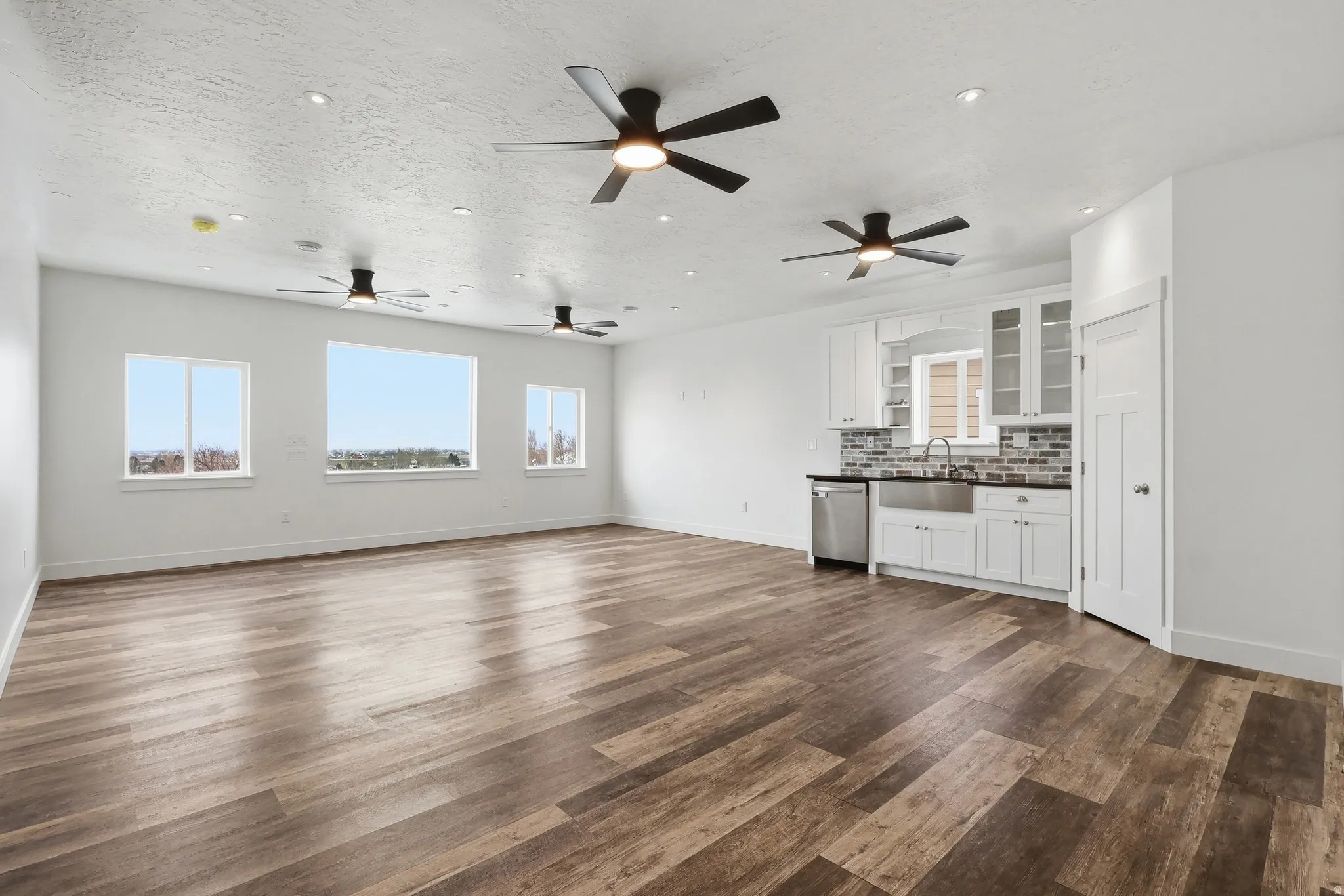 Unfurnished living room featuring plenty of natural light, dark wood-style flooring, recessed lighting, a textured ceiling, and a ceiling fan