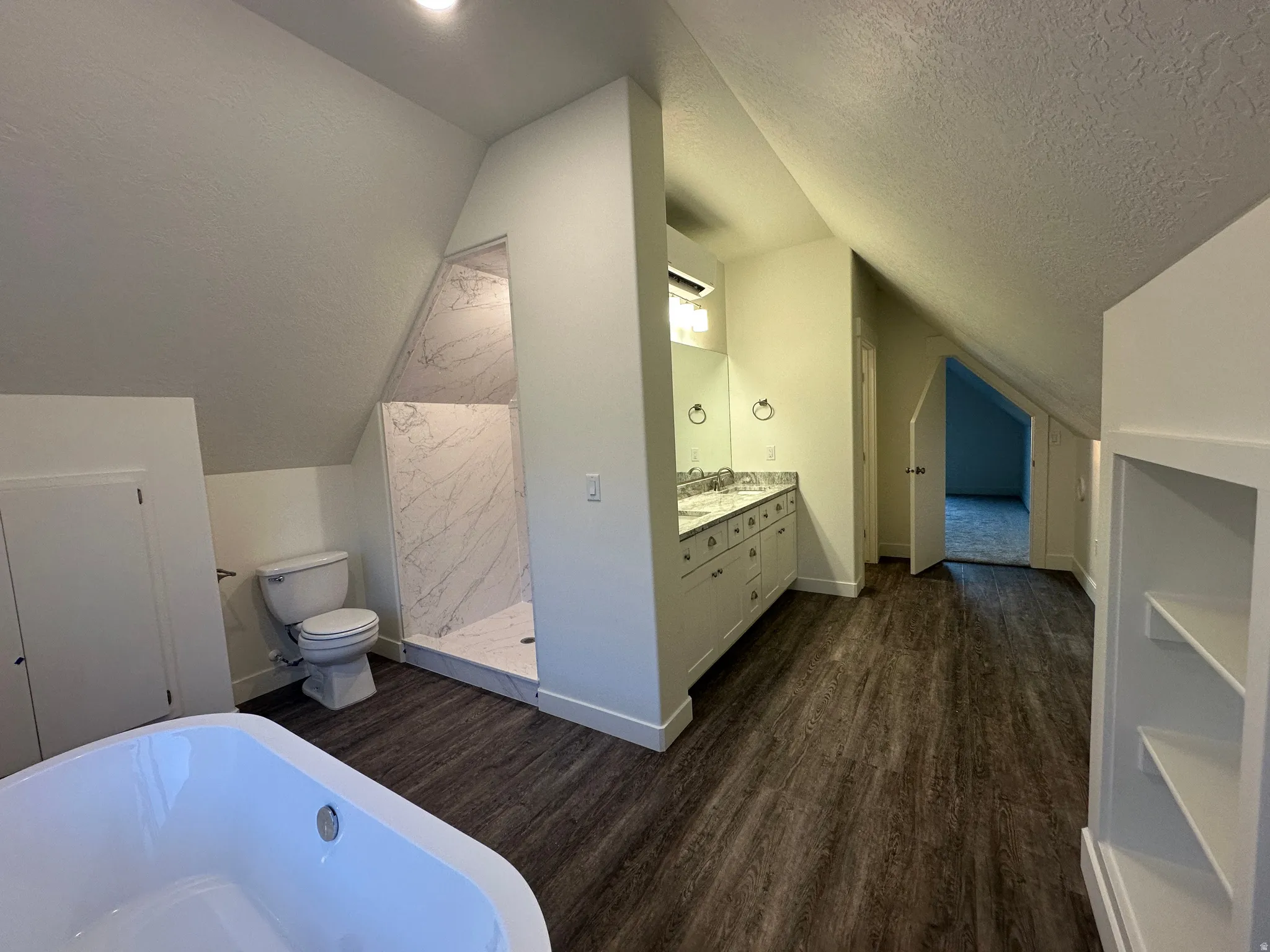 Bathroom with double vanity, a soaking tub, and marble finish shower.