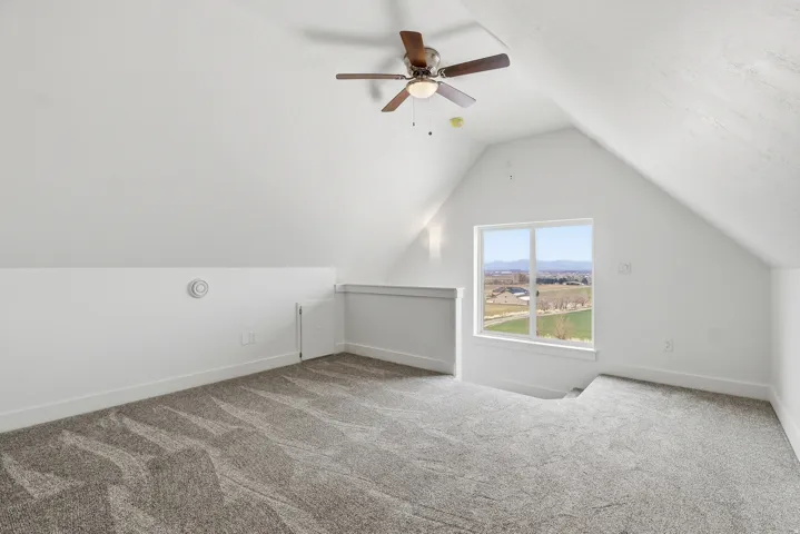 Upper level master suite featuring vaulted ceiling, light colored carpet, and ceiling fan