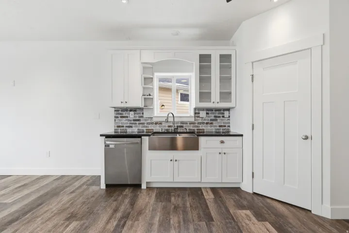 Kitchen with white cabinets, open shelves, dishwasher, and glass insert cabinets