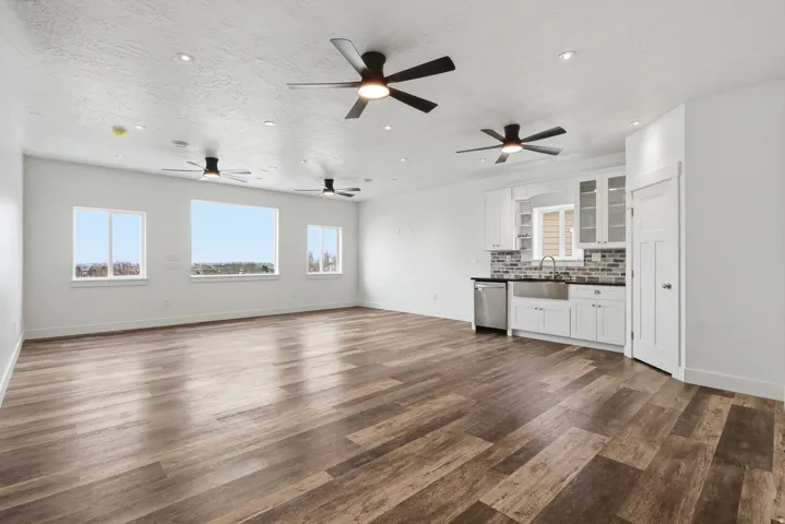 Unfurnished living room featuring plenty of natural light, dark wood-style flooring, recessed lighting, a textured ceiling, and a ceiling fan