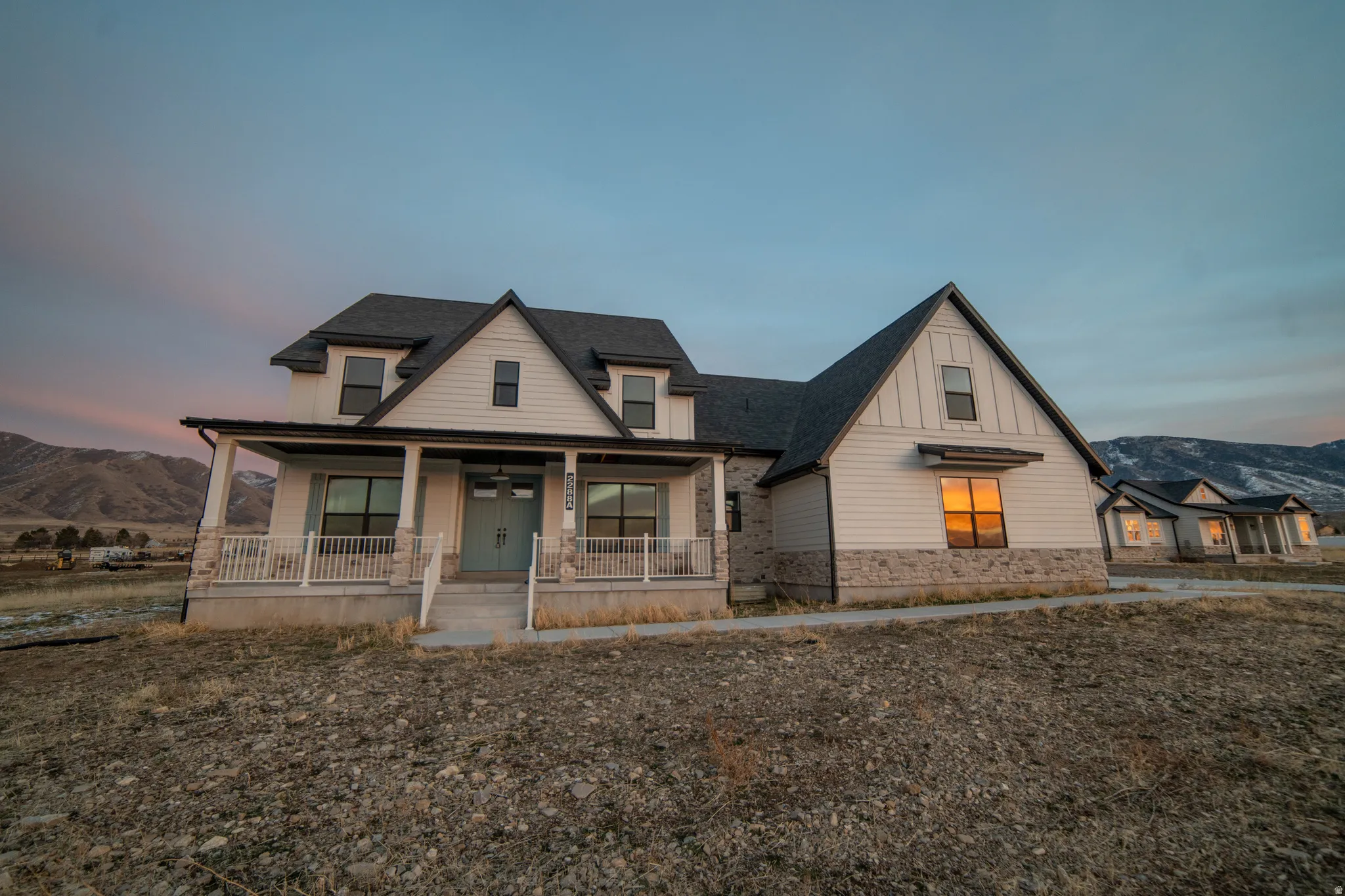 Modern farmhouse with a mountain view, a porch, roof with shingles, board and batten siding, and stone siding