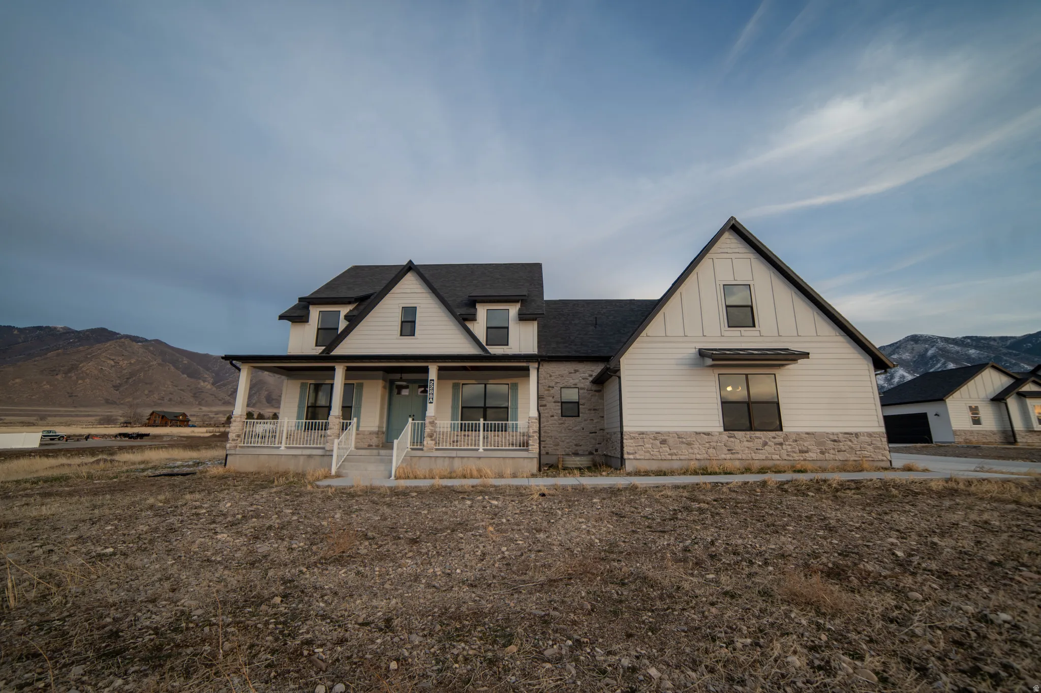Modern farmhouse style home featuring a mountain view, a porch, board and batten siding, and a shingled roof