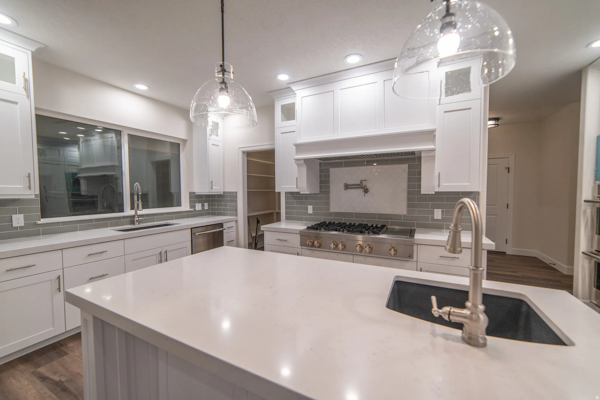 Kitchen with white cabinetry, glass insert cabinets, pendant lighting, dark wood-type flooring, and light stone counters