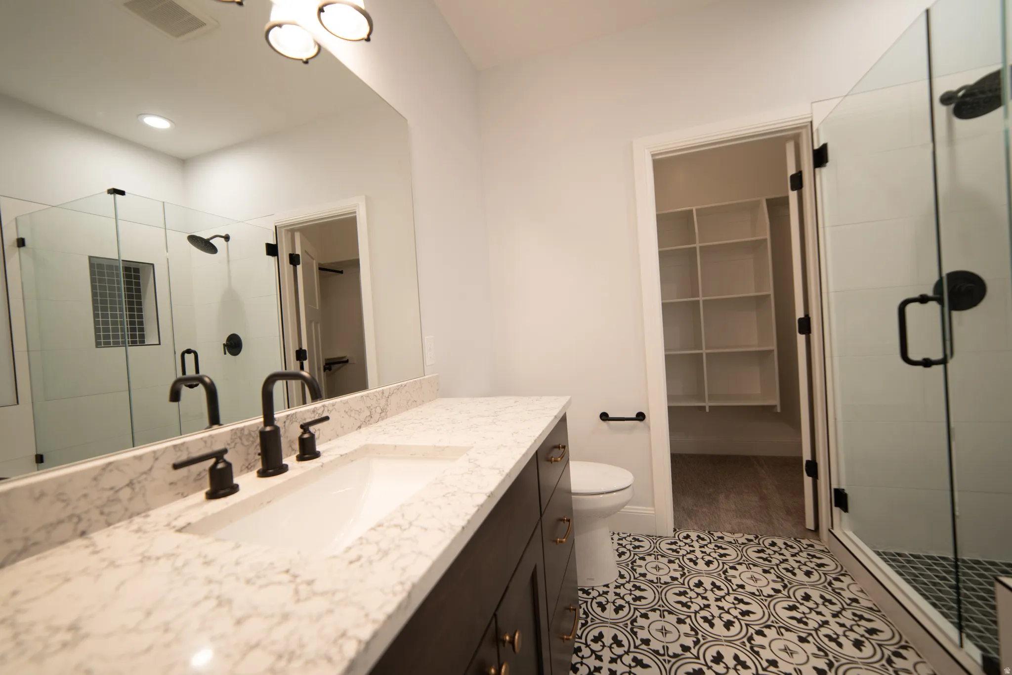 Bathroom with a stall shower, a walk in closet, vanity, and light tile patterned flooring