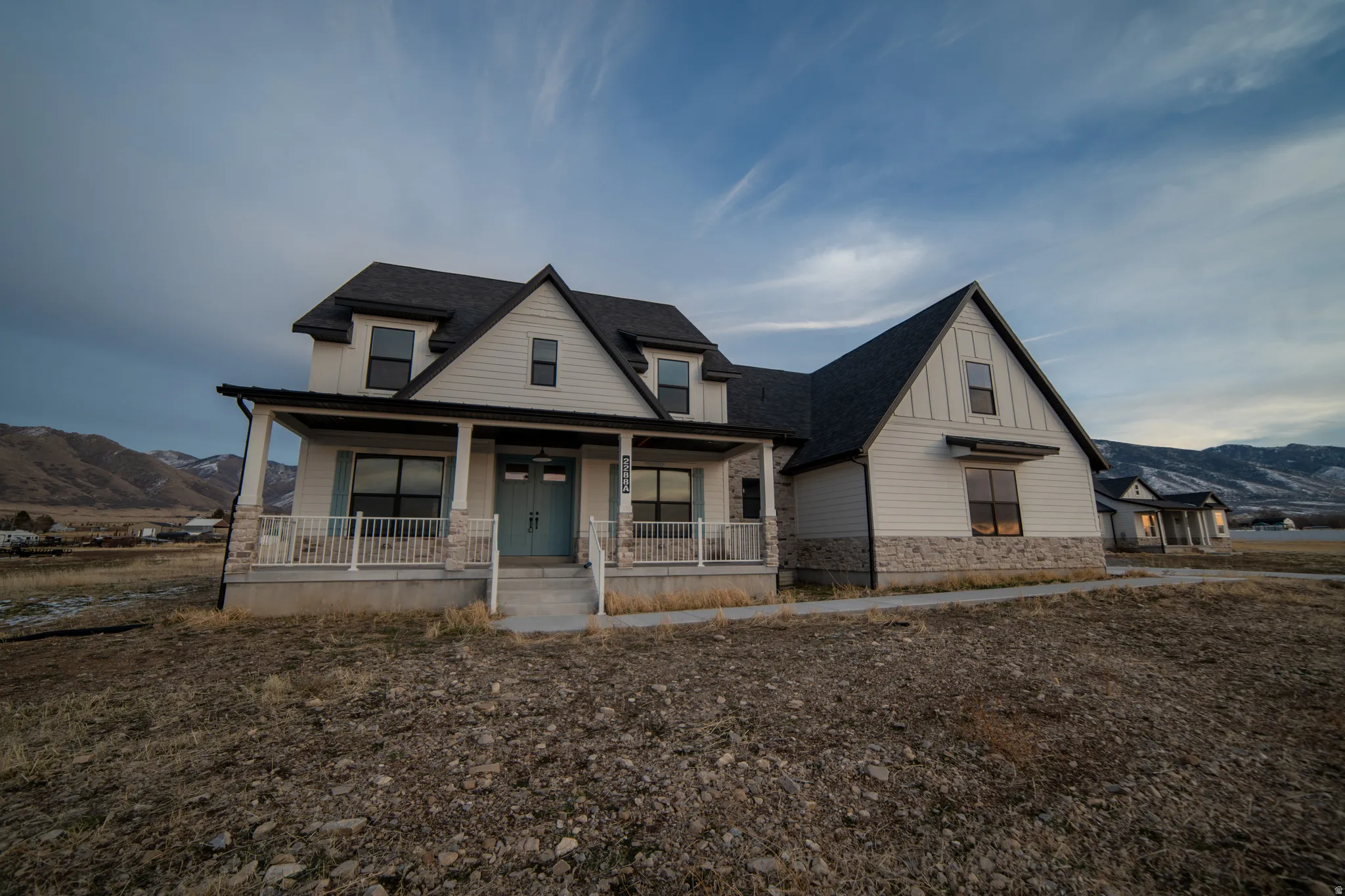 View of front of property featuring a mountain view, covered porch, a shingled roof, and stone siding