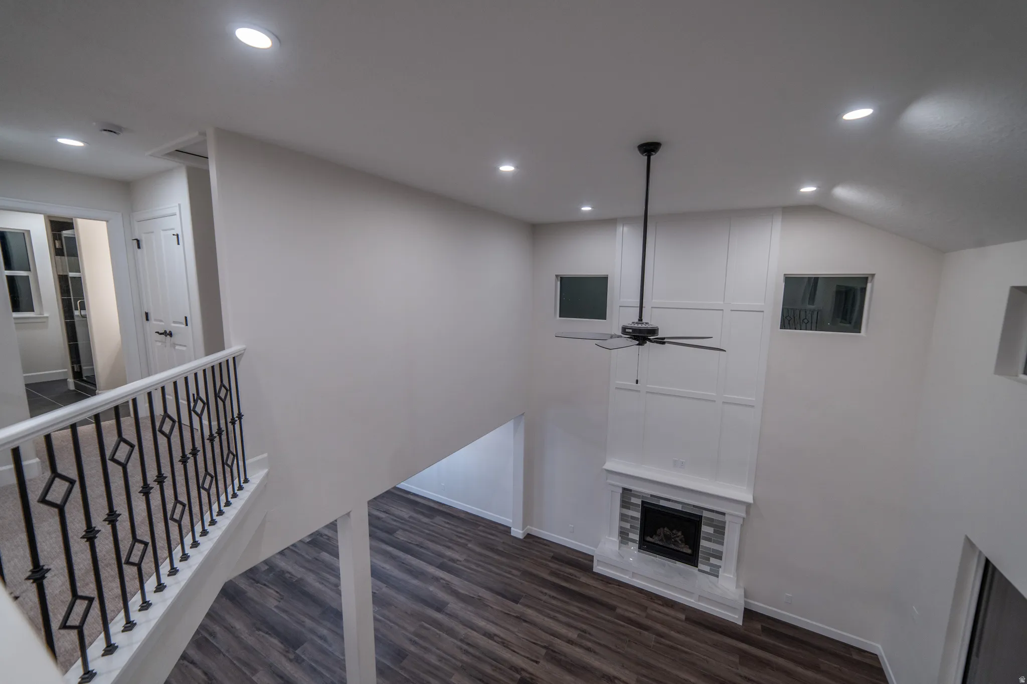 Hallway with dark wood finished floors, recessed lighting, an upstairs landing, and vaulted ceiling