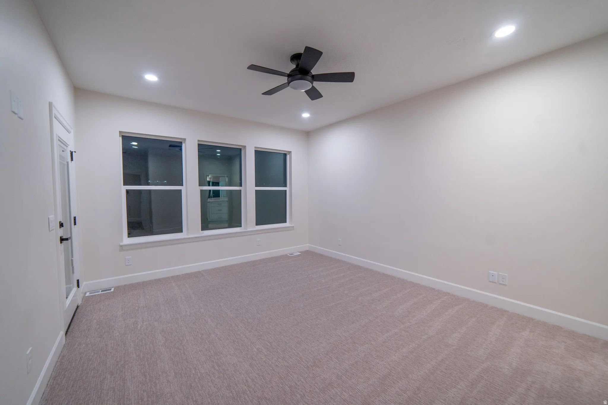 Empty room featuring light colored carpet, ceiling fan, and recessed lighting