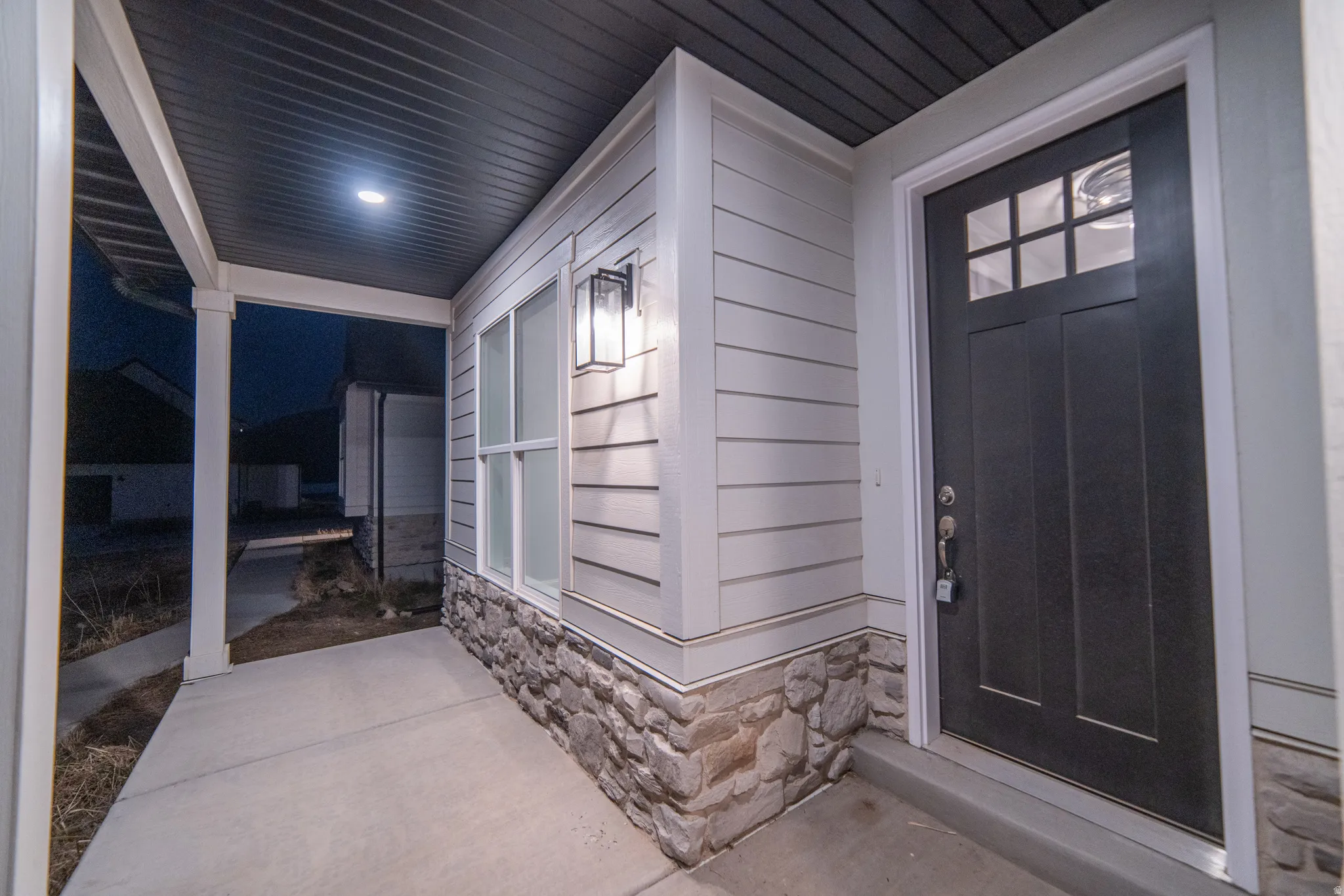 Exterior entry at twilight with stone siding and a porch