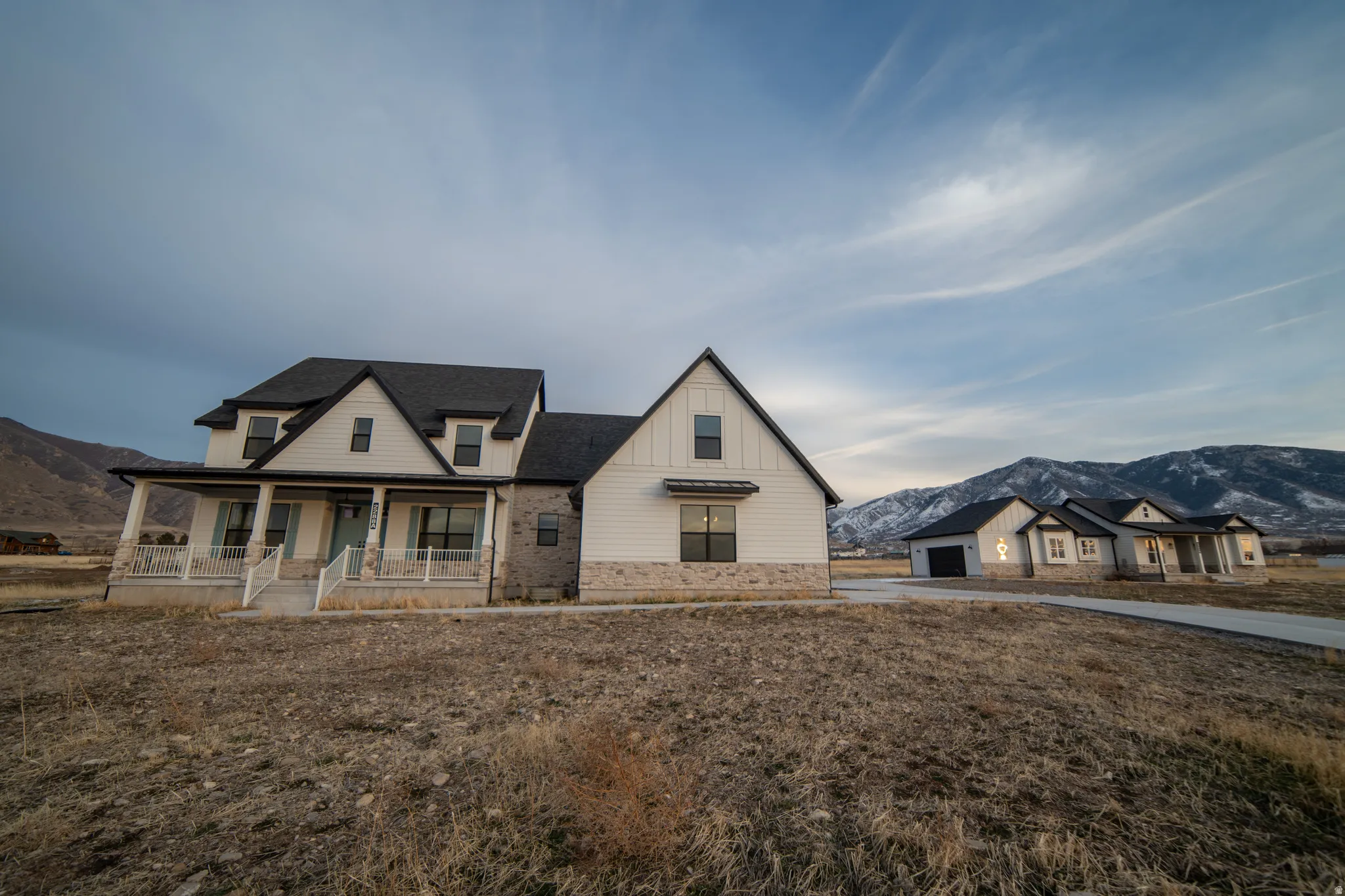 Modern farmhouse style home with a mountain view, a porch, an outbuilding, and board and batten siding