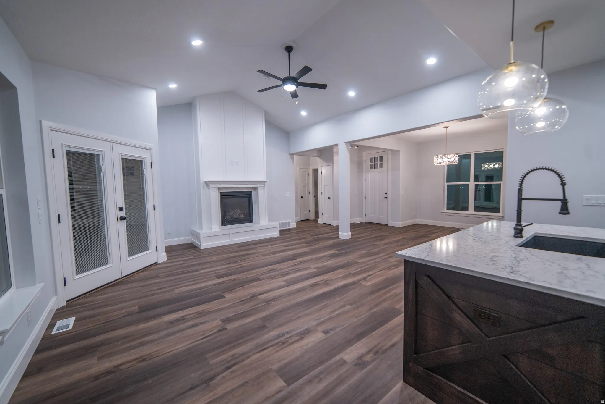 Living room with a glass covered fireplace, vaulted ceiling, dark wood finished floors, ceiling fan, and recessed lighting