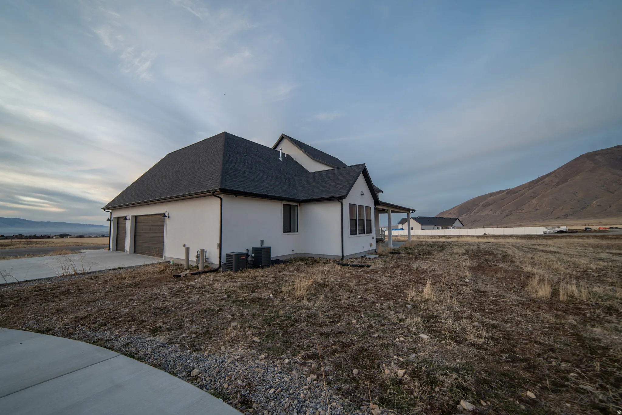 View of home's exterior featuring a mountain view, driveway, a shingled roof, an attached garage, and stucco siding