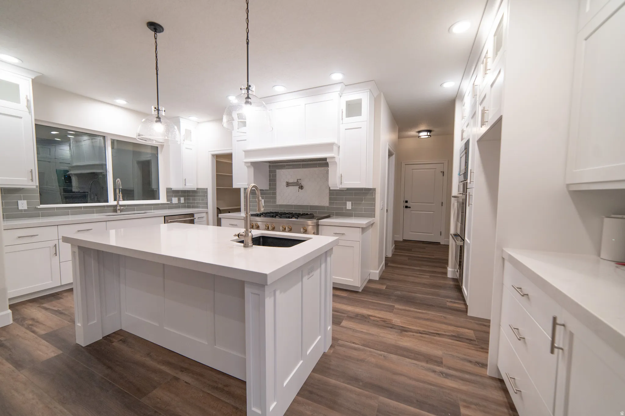 Kitchen featuring glass insert cabinets, white cabinets, dark wood-style flooring, and recessed lighting