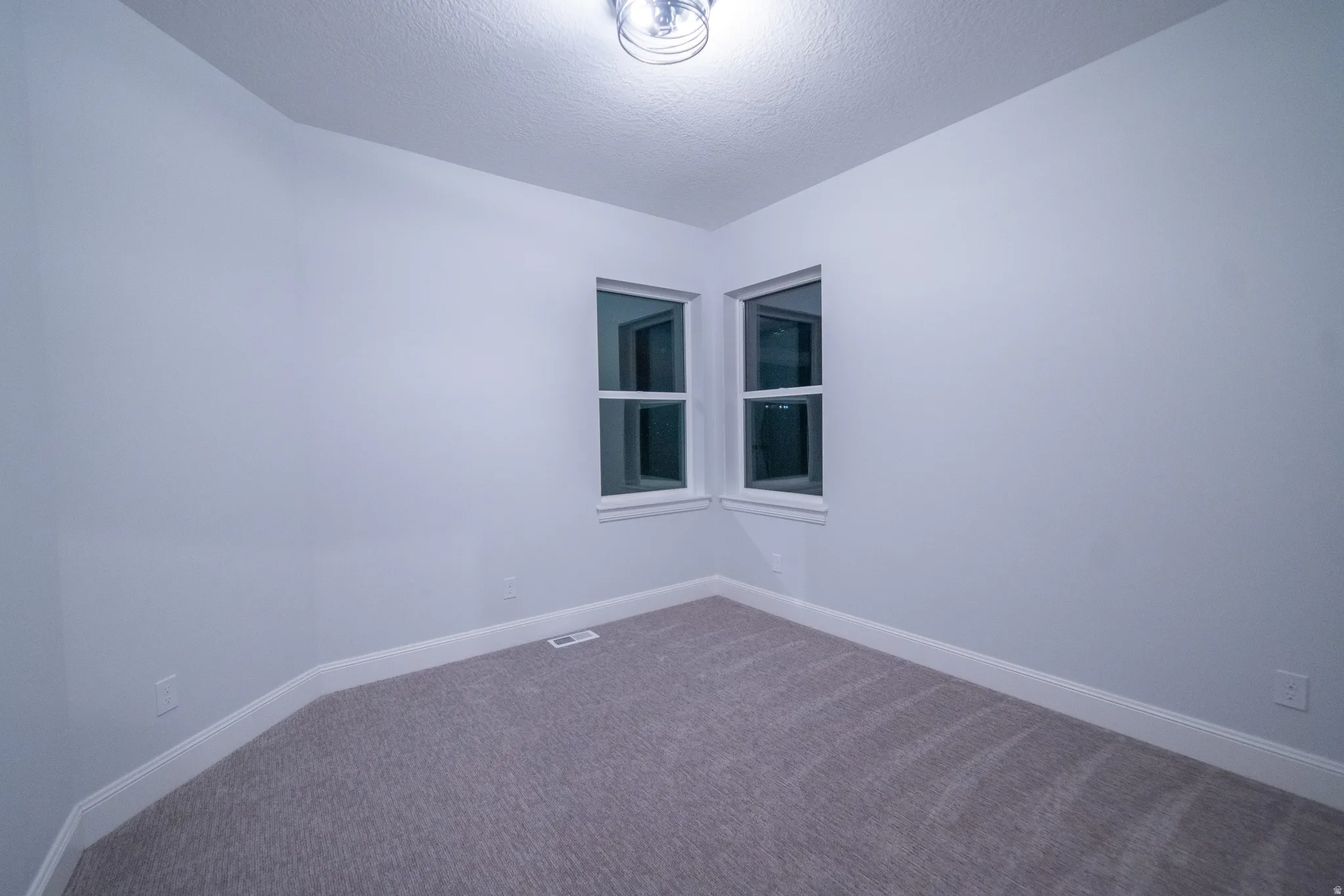 Carpeted spare room featuring baseboards and a textured ceiling