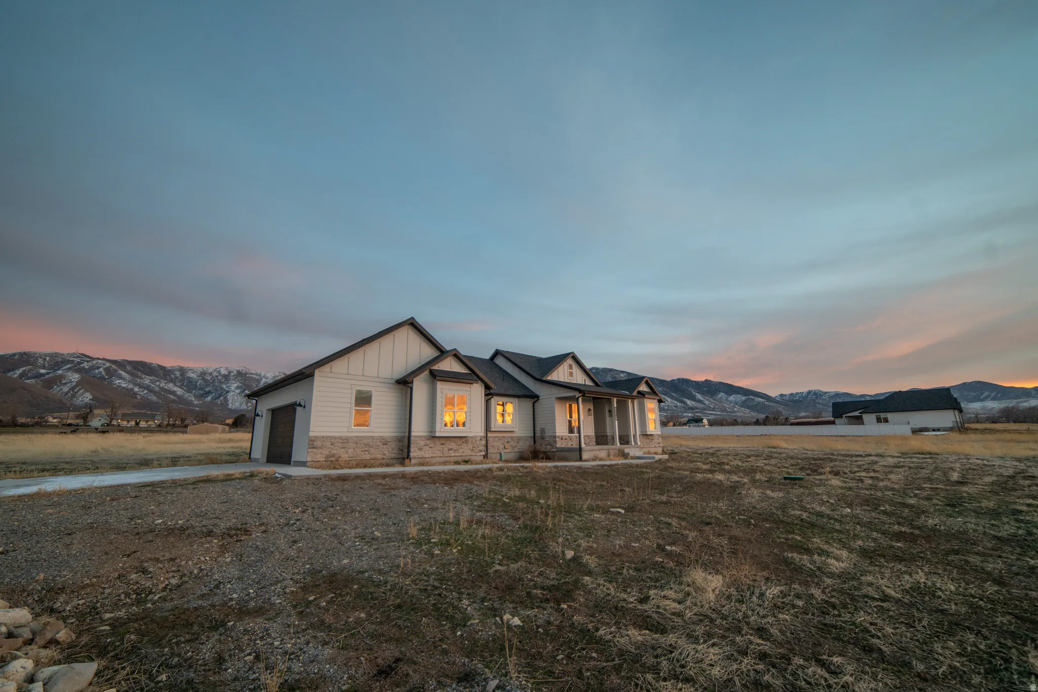 Modern farmhouse style home with stone siding, board and batten siding, a mountain view, an attached garage, and a porch