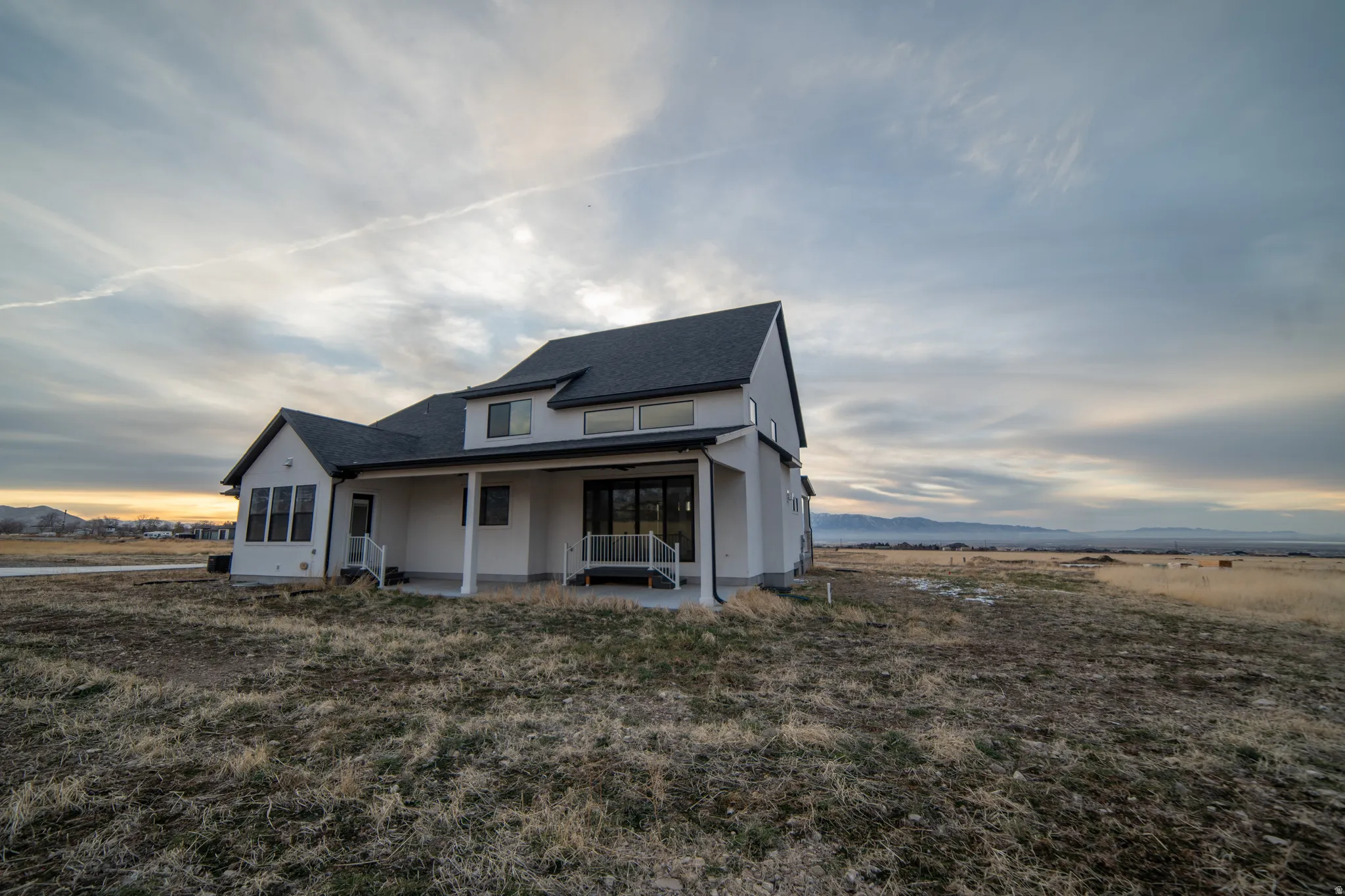 View of front of property with a patio, a mountain view, and a shingled roof